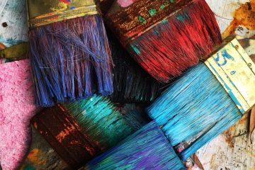 photo of paint brushes with different coloured paints, for blog post on colour psychology, paint your home happy